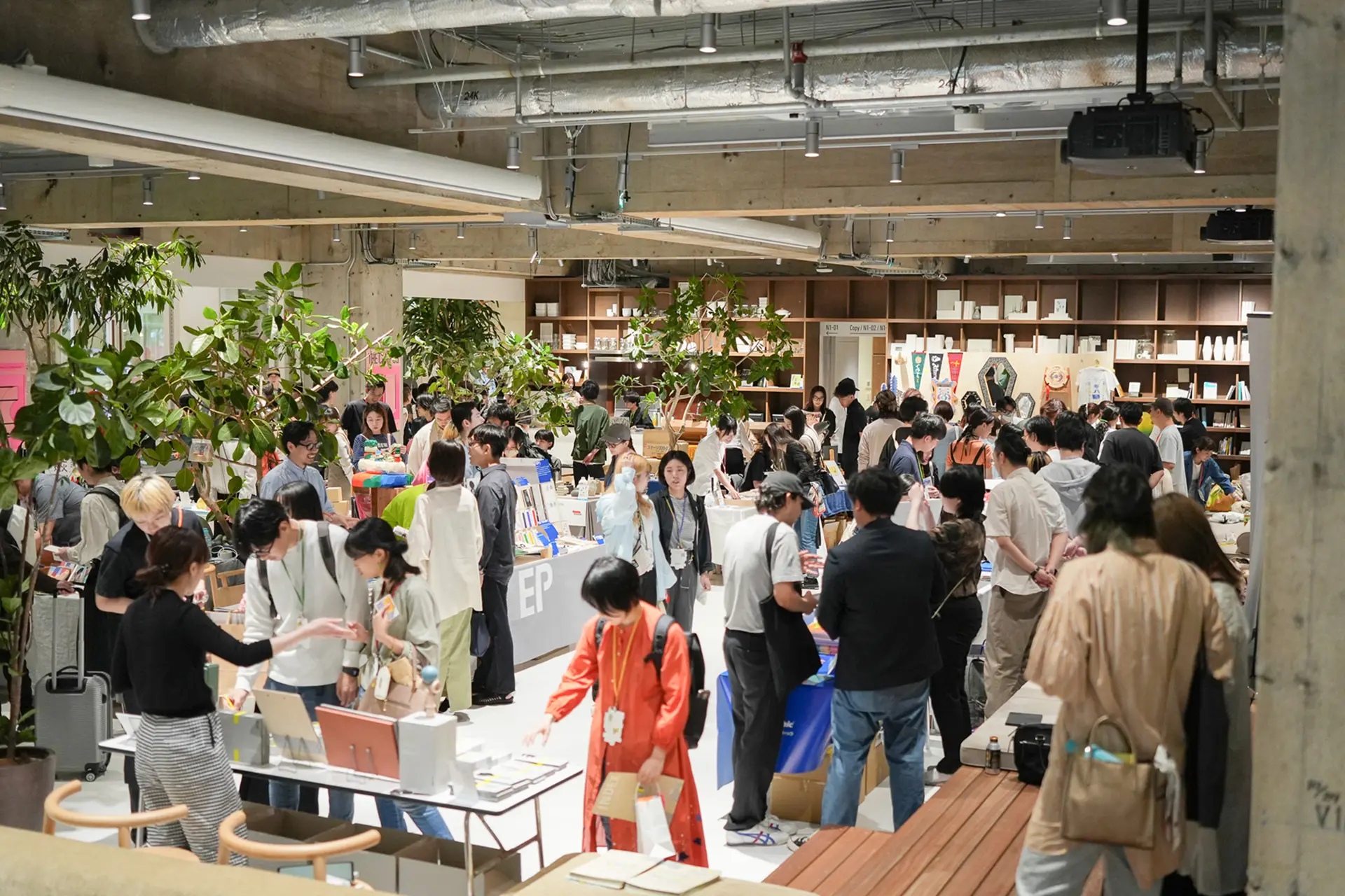 過去のクリエイターズマーケットの様子。会場内に複数のブースが並んでおり、来場者がブースを回って作品を見ている。クリエイターは、来場者に向けて作品の説明をしている。
